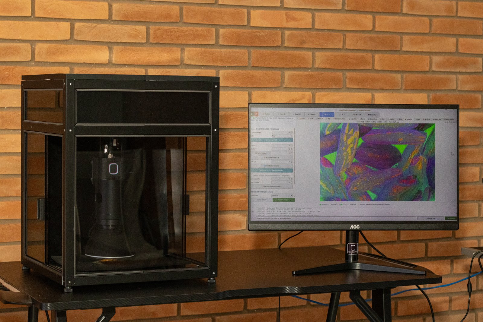 Microscópio multiespectral automatizado sobre a bancada, com o monitor mostrando a imagem da amostra