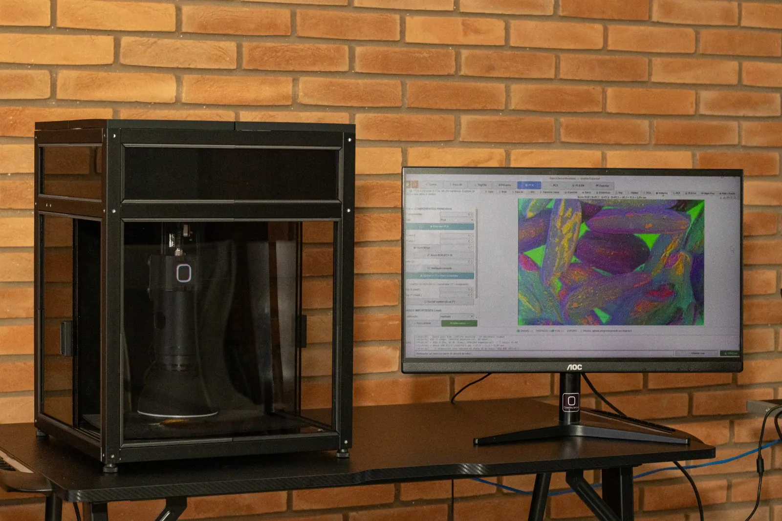 Microscópio multiespectral automatizado sobre a bancada, com o monitor mostrando a imagem da amostra